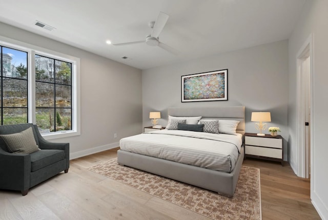 bedroom featuring ceiling fan, light hardwood / wood-style flooring, and multiple windows