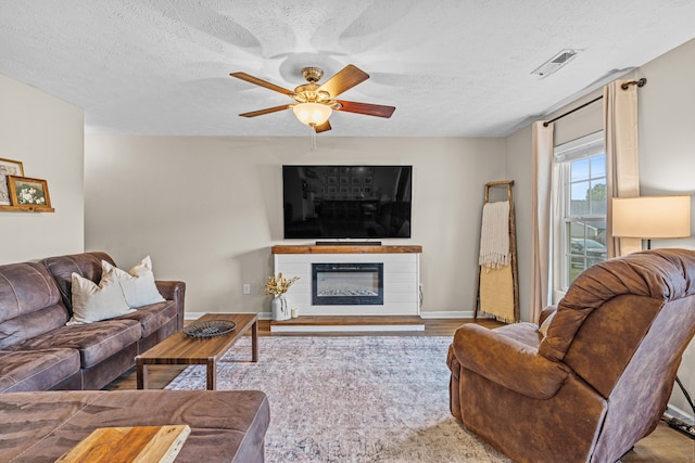 living room with ceiling fan, hardwood / wood-style flooring, and a textured ceiling