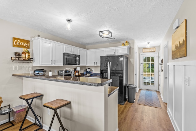 kitchen featuring stainless steel appliances, white cabinets, kitchen peninsula, and light wood-type flooring