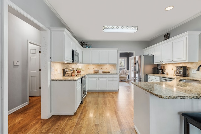 kitchen with light wood-type flooring, sink, white cabinetry, appliances with stainless steel finishes, and crown molding