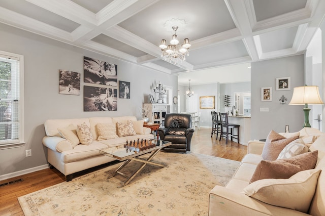 living room with beamed ceiling, ornamental molding, coffered ceiling, a notable chandelier, and light wood-type flooring