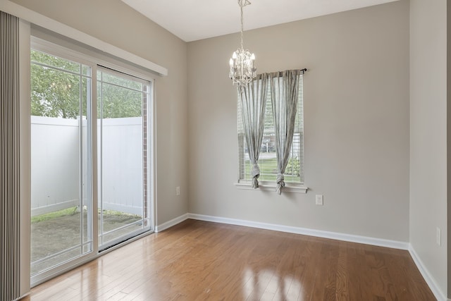 spare room featuring a notable chandelier and hardwood / wood-style flooring