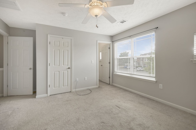 unfurnished bedroom featuring light carpet, ceiling fan, and a textured ceiling