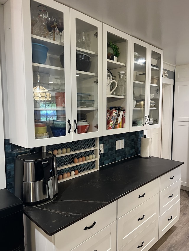 bar featuring backsplash, hardwood / wood-style flooring, and white cabinetry