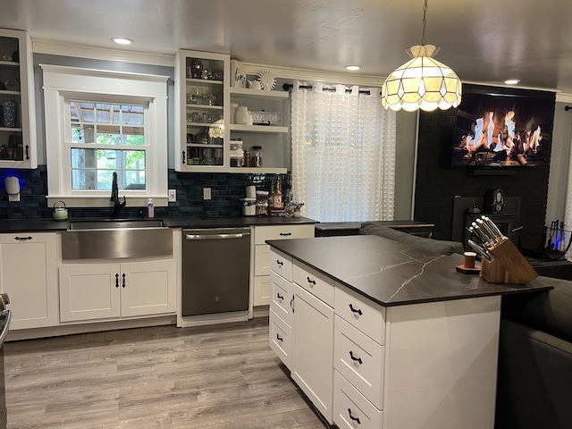 kitchen featuring stainless steel dishwasher, decorative light fixtures, white cabinetry, and sink