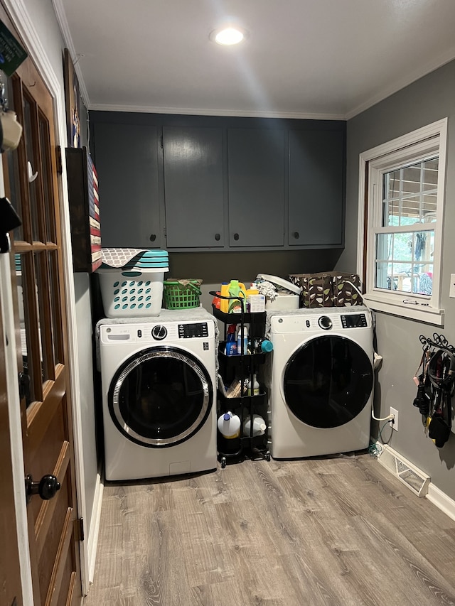 laundry area with cabinets, light wood-type flooring, crown molding, and washing machine and dryer