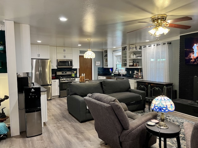 living room with light hardwood / wood-style flooring, ceiling fan, crown molding, and sink