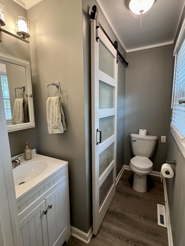 bathroom with crown molding, hardwood / wood-style floors, vanity, and toilet