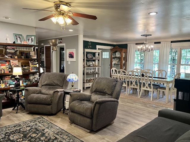 living room featuring light hardwood / wood-style floors, ceiling fan with notable chandelier, and ornamental molding