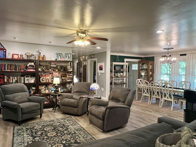 living room featuring a textured ceiling, ceiling fan with notable chandelier, and light hardwood / wood-style floors