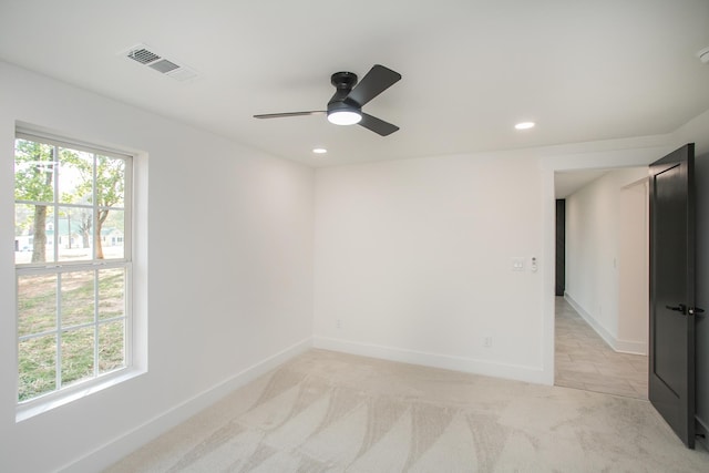 empty room featuring ceiling fan, light colored carpet, and plenty of natural light