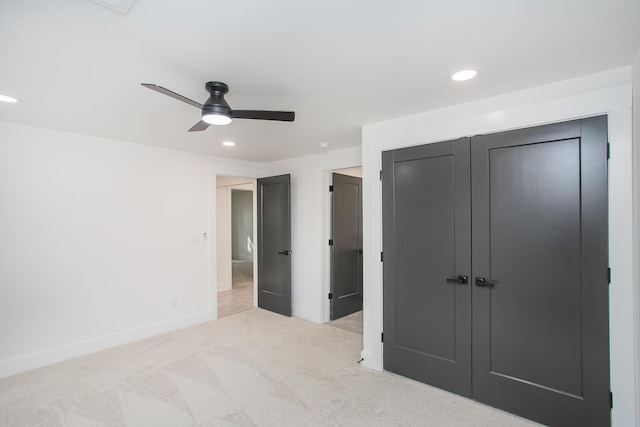 unfurnished bedroom featuring ceiling fan, light colored carpet, and a closet