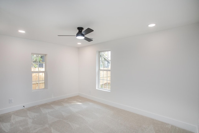 spare room with ceiling fan, plenty of natural light, and light carpet