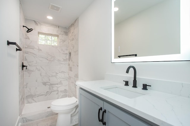 bathroom with tiled shower, vanity, and toilet