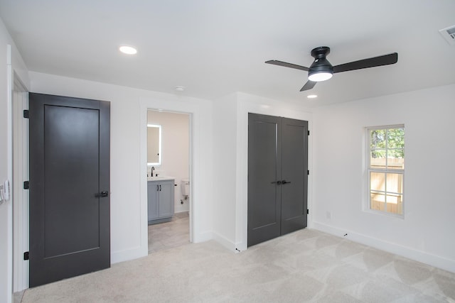 unfurnished bedroom with light carpet, ensuite bath, sink, and ceiling fan