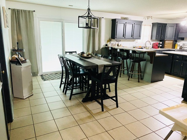 dining area featuring a notable chandelier, light tile patterned floors, and sink