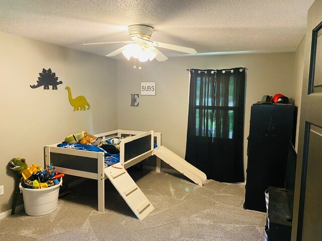 bedroom featuring ceiling fan, carpet floors, and a textured ceiling