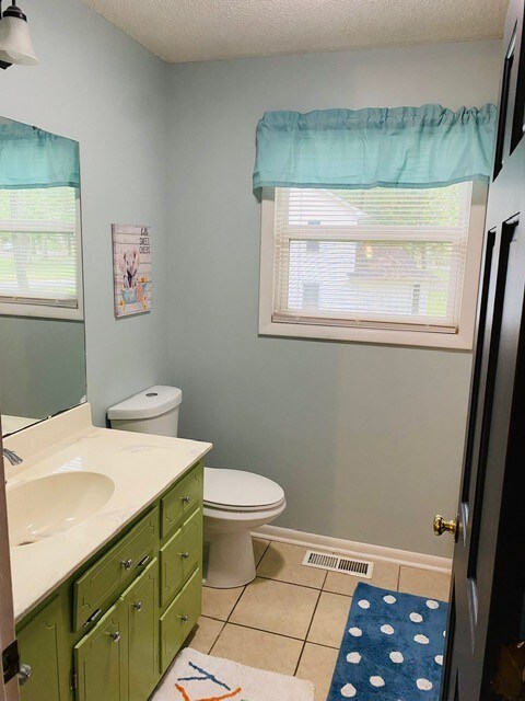 bathroom with tile patterned flooring, plenty of natural light, vanity, and toilet