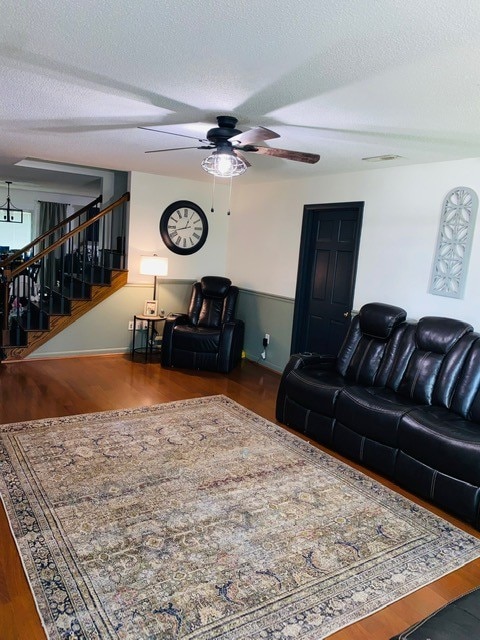 living room with ceiling fan, a textured ceiling, and hardwood / wood-style floors