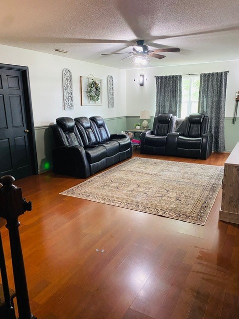 living room with ceiling fan, hardwood / wood-style flooring, and a textured ceiling