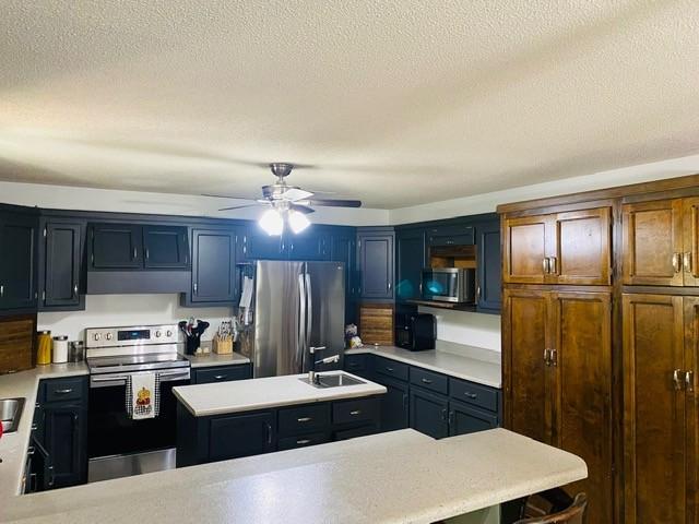 kitchen featuring a textured ceiling, sink, ceiling fan, and stainless steel appliances