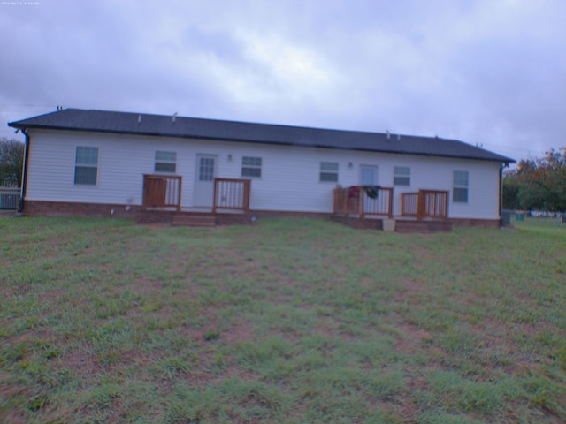 rear view of house featuring a lawn and a deck