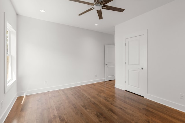 empty room with ceiling fan, a healthy amount of sunlight, and dark hardwood / wood-style flooring