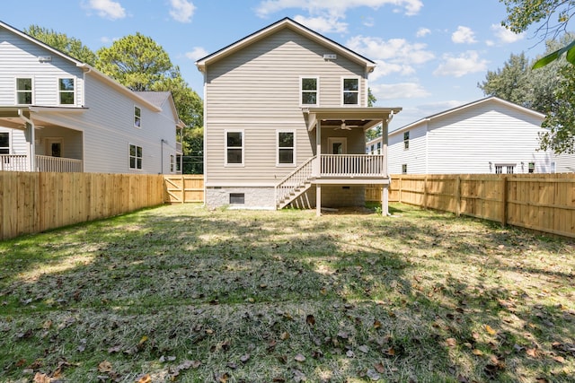 rear view of house featuring ceiling fan and a yard