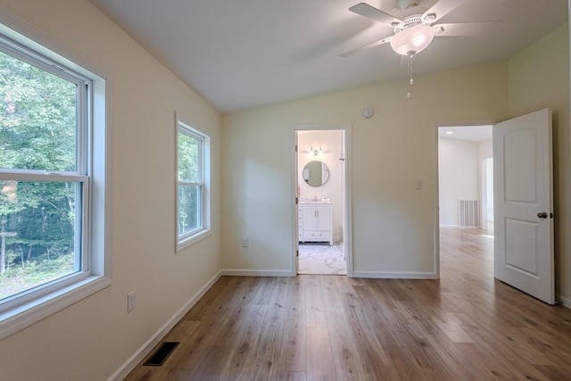 unfurnished bedroom with light wood-type flooring, vaulted ceiling, ensuite bath, and ceiling fan