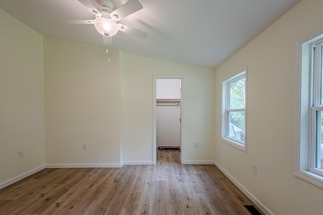 unfurnished bedroom with ceiling fan, light hardwood / wood-style flooring, a closet, a spacious closet, and vaulted ceiling