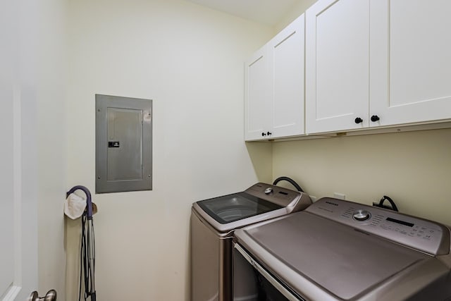 laundry room featuring electric panel, washer and dryer, and cabinets