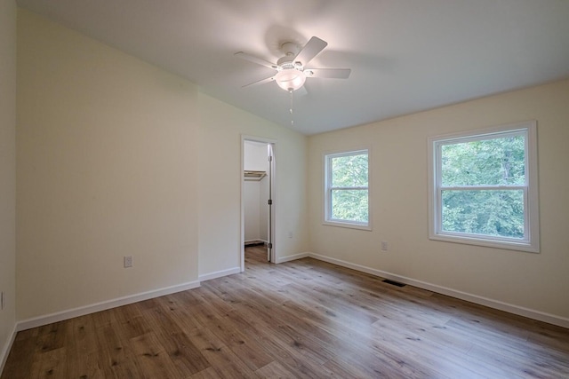 unfurnished bedroom with a spacious closet, multiple windows, light hardwood / wood-style flooring, and ceiling fan