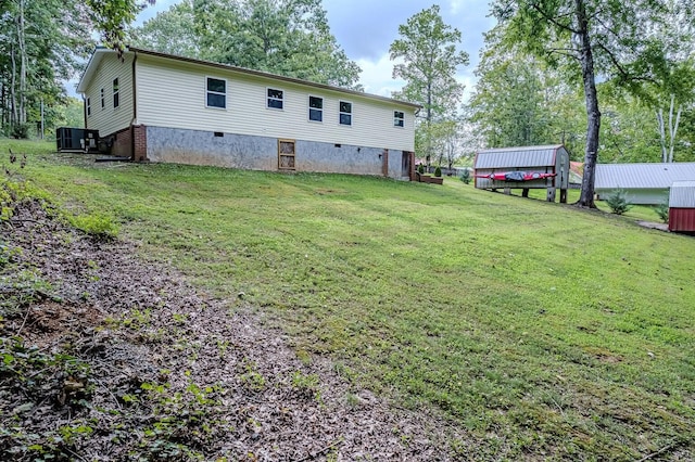 back of property with central AC unit and a yard