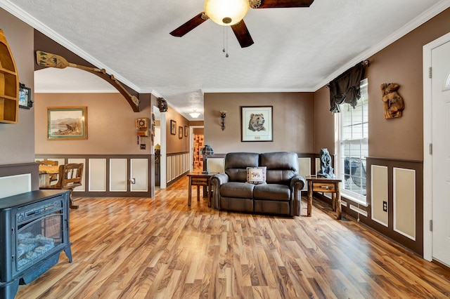 living room featuring ornamental molding, light wood-type flooring, ceiling fan, and a textured ceiling