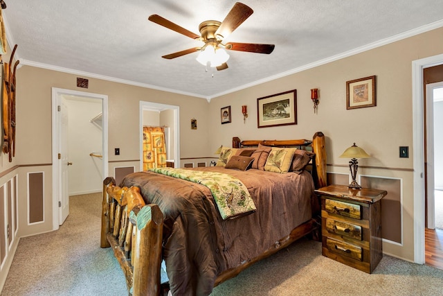 carpeted bedroom featuring ceiling fan, a textured ceiling, crown molding, and ensuite bathroom