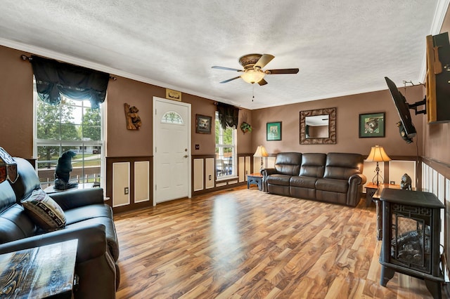 living room with light hardwood / wood-style flooring, ceiling fan, and ornamental molding