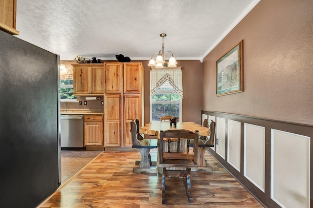 dining room with a notable chandelier, hardwood / wood-style flooring, ornamental molding, and plenty of natural light