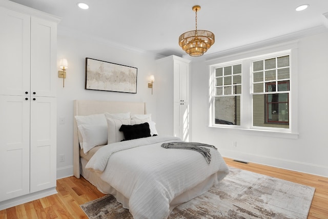 bedroom with light hardwood / wood-style flooring, crown molding, and a closet