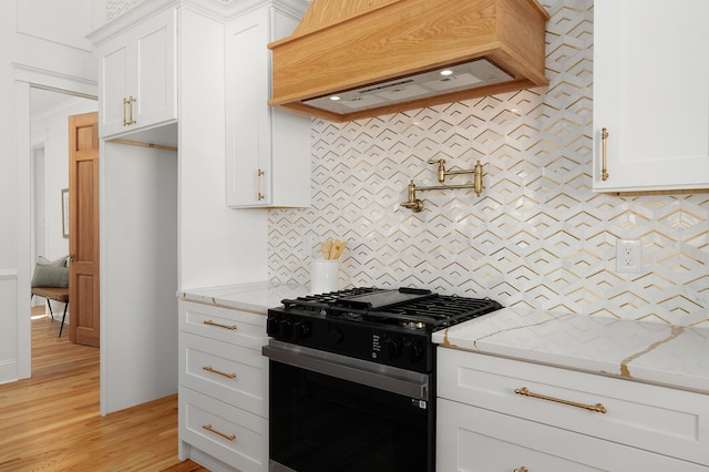 kitchen featuring light stone countertops, stainless steel gas stove, light hardwood / wood-style floors, and white cabinets