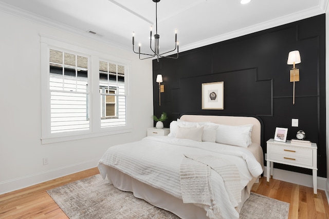 bedroom featuring light hardwood / wood-style flooring, a notable chandelier, and crown molding