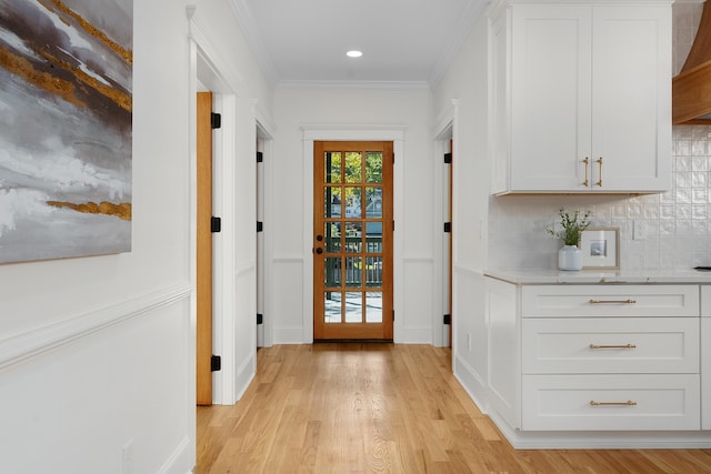 entryway with light hardwood / wood-style floors and crown molding