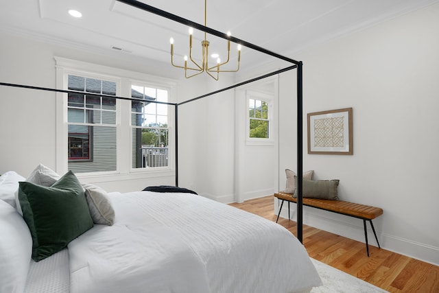 bedroom featuring ornamental molding, light hardwood / wood-style flooring, and an inviting chandelier