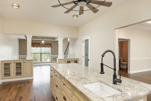 kitchen featuring sink, light stone countertops, dark hardwood / wood-style flooring, and an island with sink