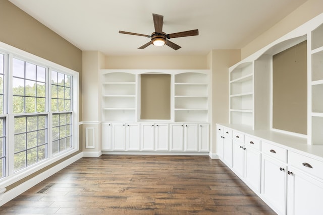 unfurnished dining area with dark wood-type flooring, ceiling fan, and built in features