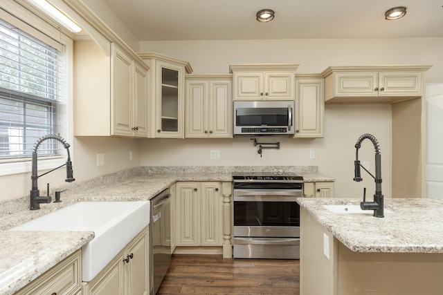 kitchen featuring light stone countertops, sink, cream cabinetry, dark hardwood / wood-style flooring, and stainless steel appliances