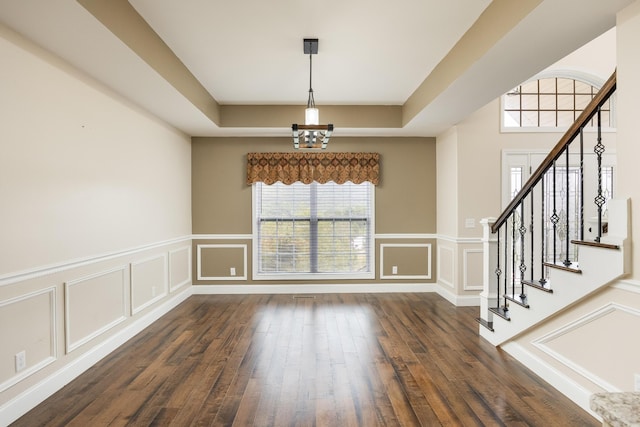 interior space with dark hardwood / wood-style floors and a tray ceiling