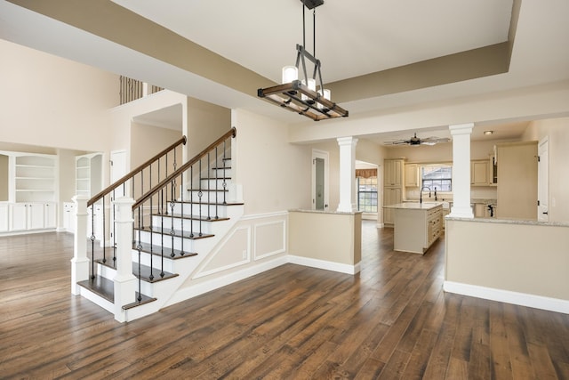 stairway with ornate columns, sink, hardwood / wood-style floors, built in shelves, and ceiling fan