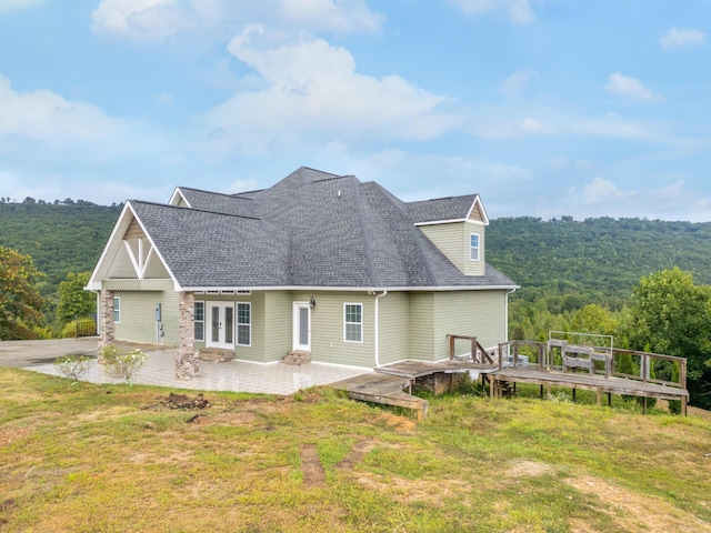 back of property with a wooden deck, a patio, and a lawn