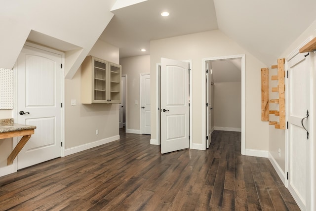 interior space featuring connected bathroom, vaulted ceiling, and dark hardwood / wood-style flooring