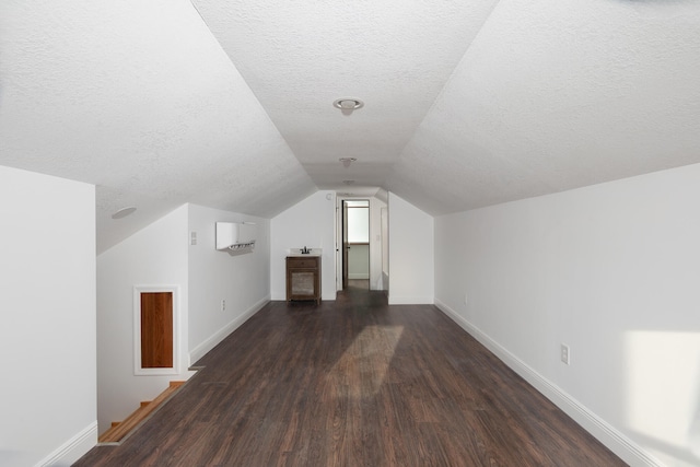 additional living space with lofted ceiling, a textured ceiling, and dark hardwood / wood-style flooring